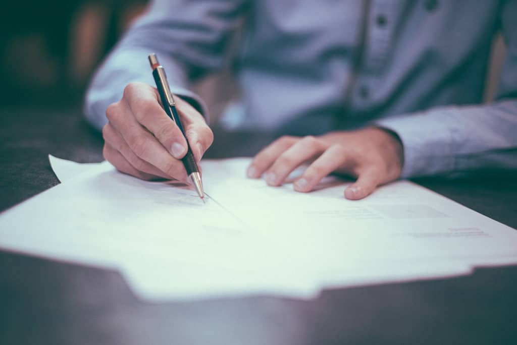 Close up image of a man writing on a paper on the paper